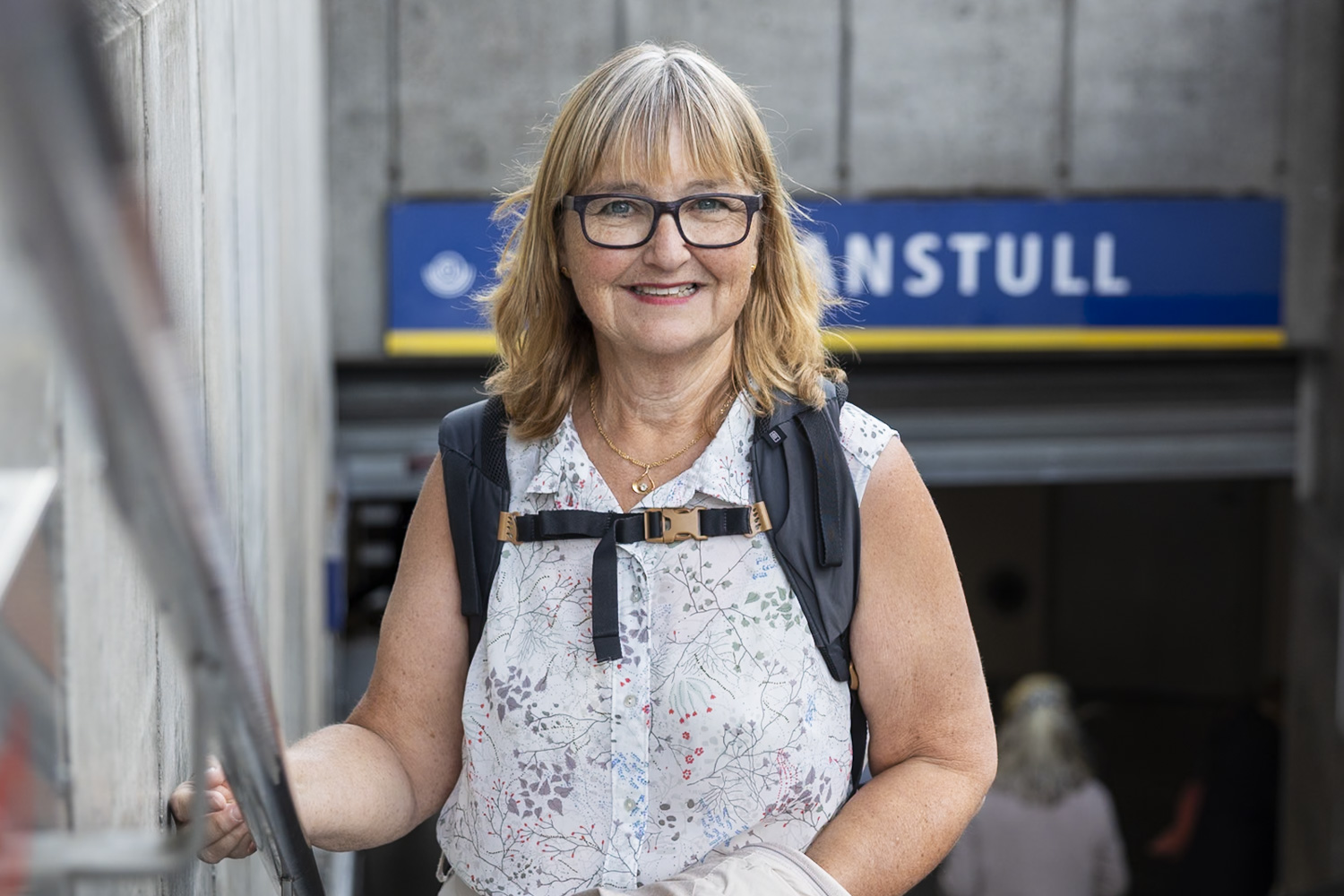 Äldre kvinna med ryggsäck som står utanför tunnelbanestationen skanstull i stockholm
