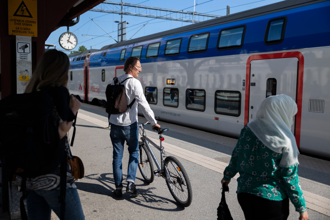 Man med cykel på perrong med ett Mälartåg i bakgrunden