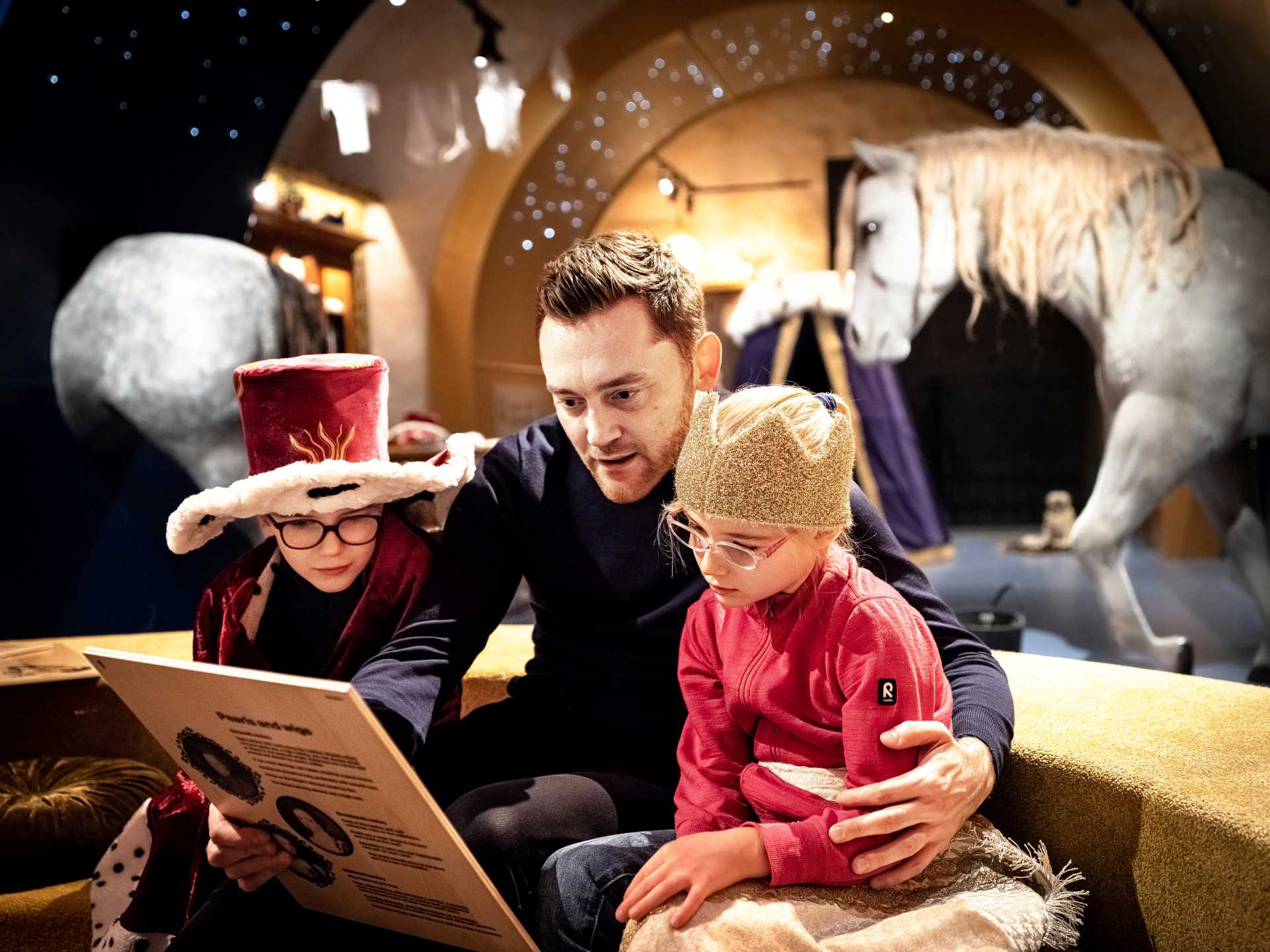 Utklädda barn med man läser tillsammans på Livrustkammaren.