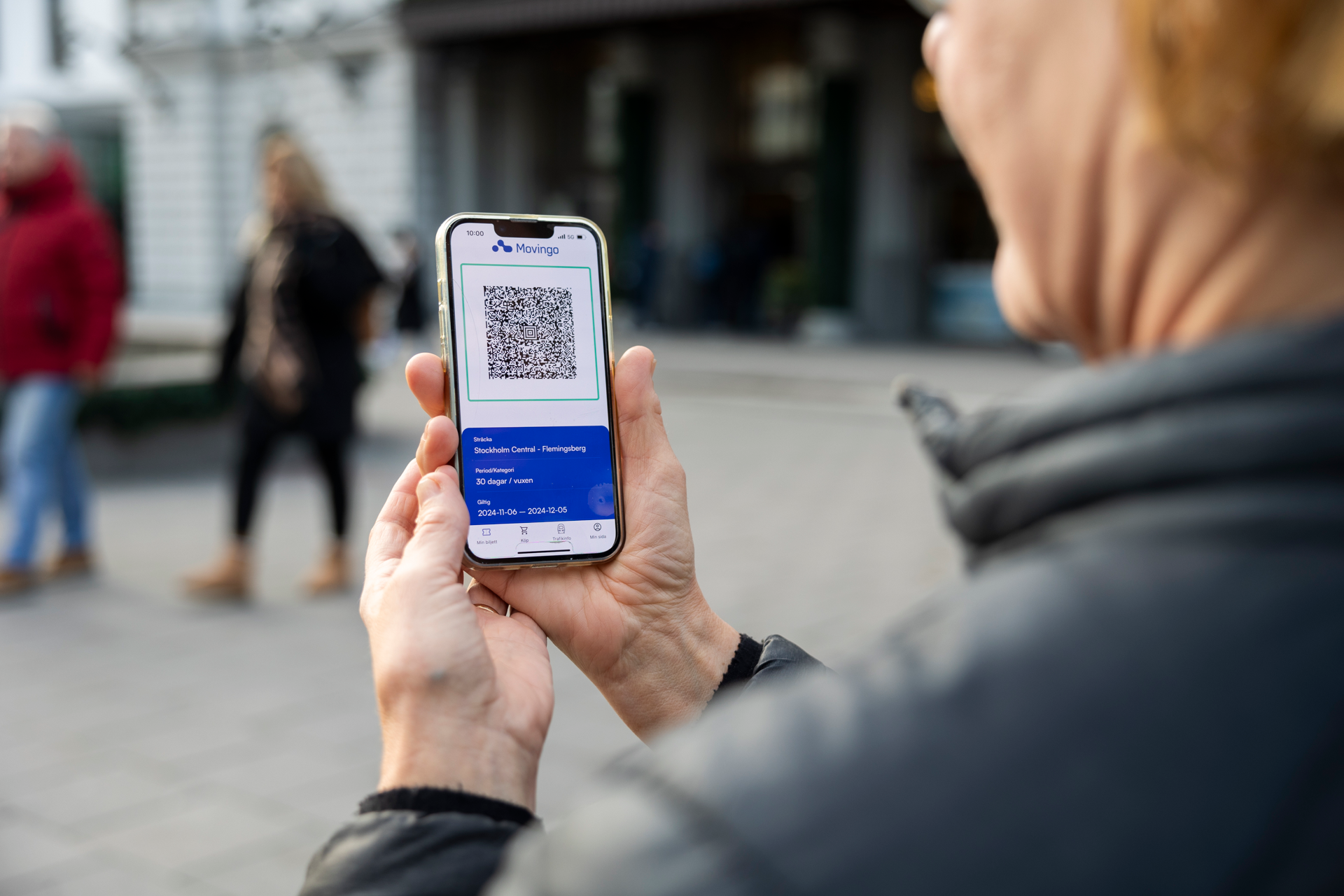 En person som håller i en mobiltelefon med en qr-kod på skärmen