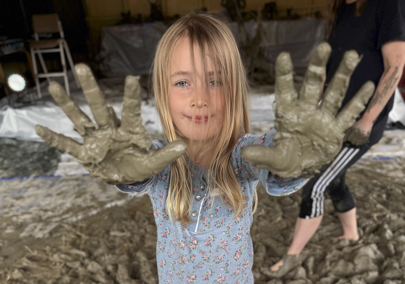 Flicka som visar upp sin leriga händer.